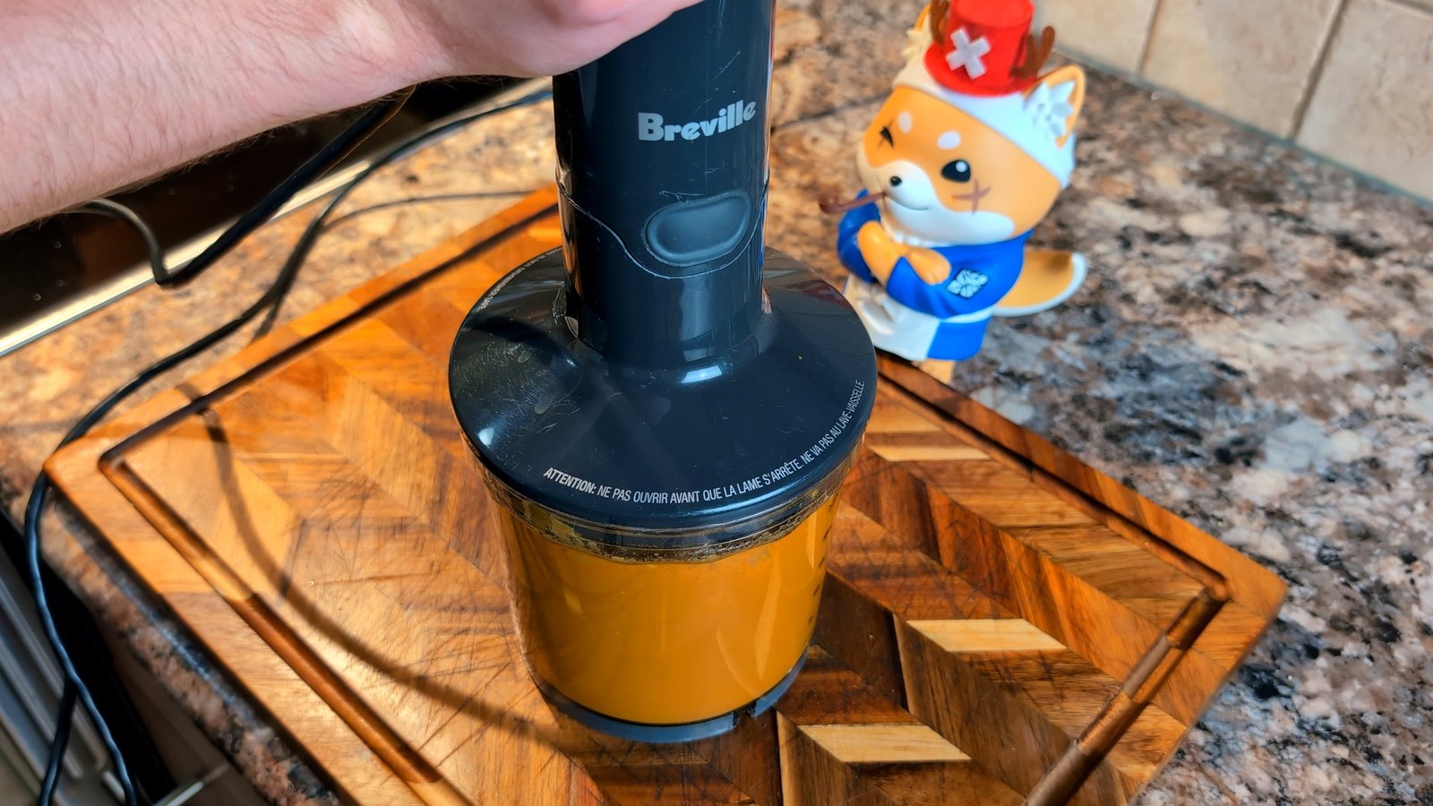 Using a hand-held immersion blender to puree the vibrant orange makhani sauce until perfectly smooth.